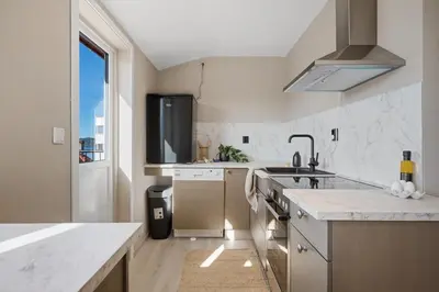 a white kitchen with a sink and a window at Toppleilighet på Sandviken med balkong in Bergen