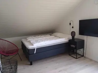 a bed in a room with a tv and a chair at Holiday home near all facilities in Grinde, Aksdal in Tysvær