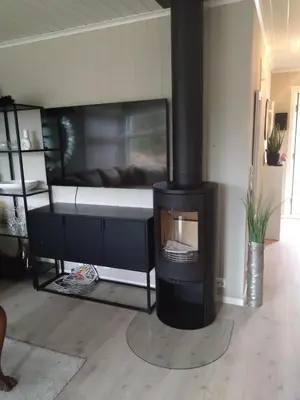 a living room with a fireplace with a bed in the background at Holiday home near all facilities in Grinde, Aksdal in Tysvær