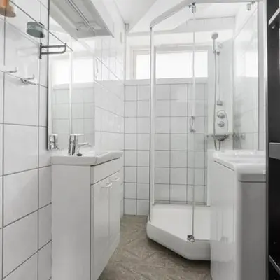 a white bathroom with a shower and a sink at Central 4 room apartment in Bergen