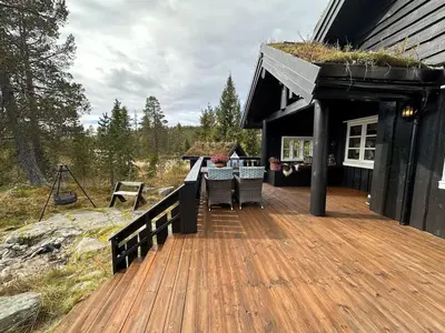 a house with a wooden deck with a table on it at Cosy cabin in Eggedal