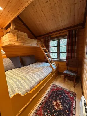 a bedroom in a cabin with a bed and a chair at Cosy cabin in Eggedal
