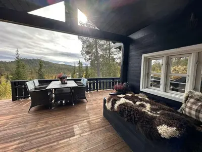 a room with a deck with a table and a couch at Cosy cabin in Eggedal