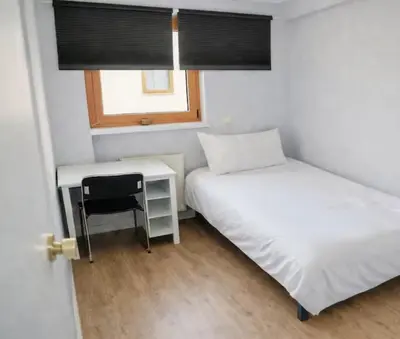 a bedroom with two beds and a desk and a window at House 2 rooms in Trondheim