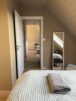 a bedroom with a bed and a large mirror at Cozy loft apartment in the heart of Bergen in Bergen