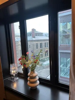 a vase with flowers on a table in front of a window at Great apartment in the center of Ålesund in Ålesund
