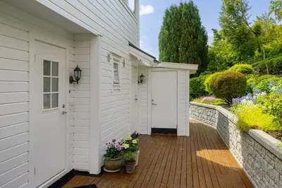 a white house with a white door and a brick fence at Central apartment with parking in unique surroundings in Bergen