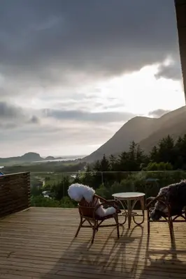 two chairs and a table on a deck with mountains at Large house with Ocean view at Ervik and Vestkapp