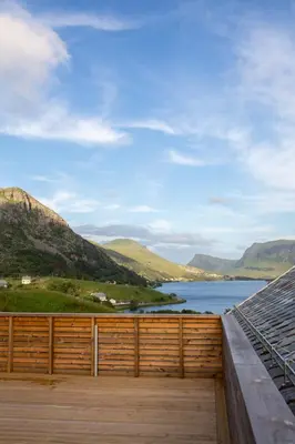 a deck with a view of the water and mountains at Large house with Ocean view at Ervik and Vestkapp