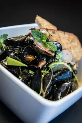 a bowl of mussels and bread with a salad at Hjorten Hotell Hitra in Fillan