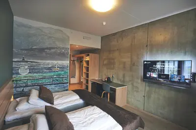 a bedroom with a bed and a tv on a wall at Hjorten Hotell Hitra in Fillan