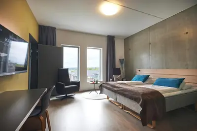 a bedroom with a bed and a desk and a chair at Hjorten Hotell Hitra in Fillan