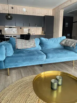 a blue couch in a living room with a table at Ski-in & out Totten Lodge apartment two bedrooms in Hemsedal