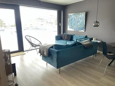 a living room with a blue couch and a large window at Ski-in & out Totten Lodge apartment two bedrooms in Hemsedal