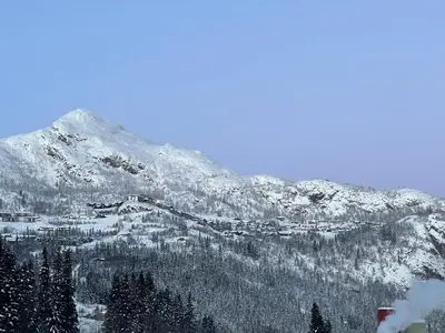 a snow covered mountain with a town in front of it at Ski-in & out Totten Lodge apartment two bedrooms in Hemsedal