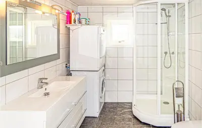 a white bathroom with a sink and a refrigerator at Beautiful Home In Fitjar in Fitjar