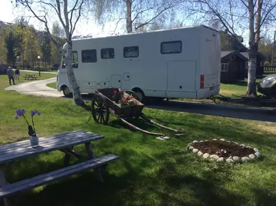 a trailer parked next to a picnic table and a bench at Furuly Camping in Nordberg
