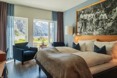 a bedroom with a large bed and a chair at Valldal Fjordhotell - by Classic Norway Hotels in Valldal