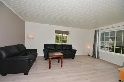 a living room with black leather couches and a table at Villa Haudalan Åndalsnes in Åndalsnes