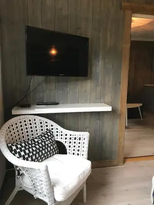 a living room with a wicker chair and a television on a wall at Kvamseter Lodge in Kvamseter