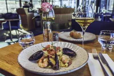 a table with two plates of food and a glass of wine at Prize by Radisson, Solheimsviken Bergen in Bergen