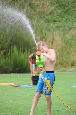 a young boy spraying himself with a water hose at Lauvøy Feriesenter in Askøy
