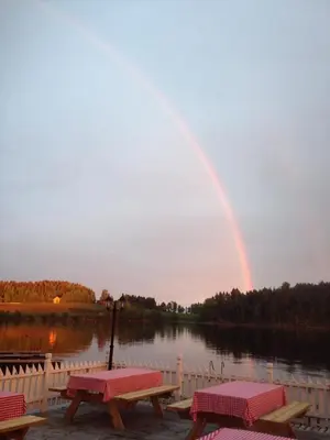a rainbow in the sky over a lake with picnic tables at Steinvik Camping in Moelv