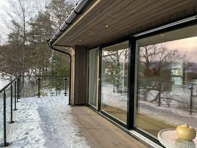 a house with glass doors and snow on the porch at Bosdalhuset in Lavik