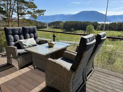 a patio with wicker chairs and a table on a deck at Bosdalhuset in Lavik