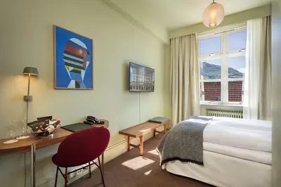 a hotel room with a bed and a desk and a window at Grand Hotel Terminus in Bergen