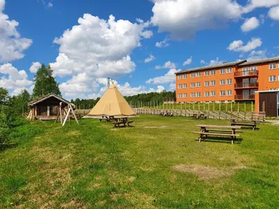 a group of picnic tables in a field with a building at Røros Hotell - Bad & Velvære in Røros