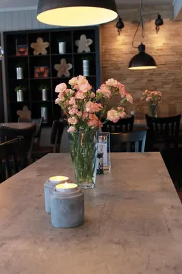a vase of pink flowers sitting on a table at Lampeland Hotel in Lampeland