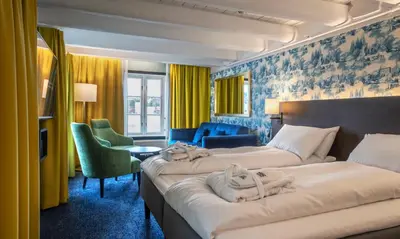 two beds in a hotel room with yellow curtains at Thon Hotel Kristiansund in Kristiansund
