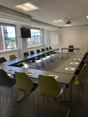 a classroom with long tables and chairs and a whiteboard at Thon Hotel Victoria Hamar in Hamar