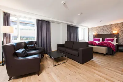 a bedroom with a bed and a couch and a chair at Thon Hotel Victoria Hamar in Hamar