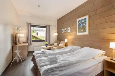 a bedroom with a large bed with a wooden wall at Highland Lodge in Geilo