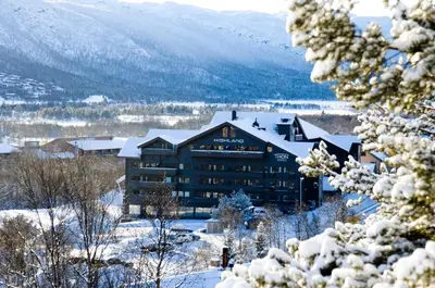 a hotel in the snow with mountains in the background at Highland Lodge in Geilo