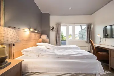 a bedroom with a large white bed and a desk at Highland Lodge in Geilo