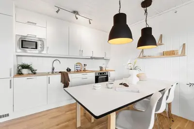a kitchen with white cabinets and a white table and chairs at Voss Resort self-service apartments in Skulestadmo