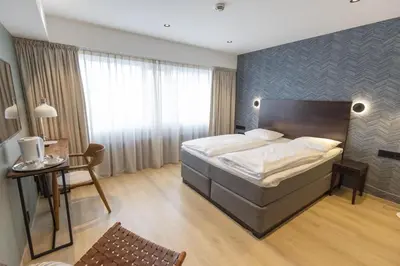 a bedroom with a bed and a table and a chair at Scandic Victoria Florø in Florø