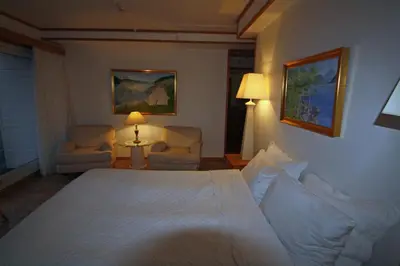 a bedroom with a white bed and two chairs at Sunde Fjord Hotel, free and easy parking in Solavagen