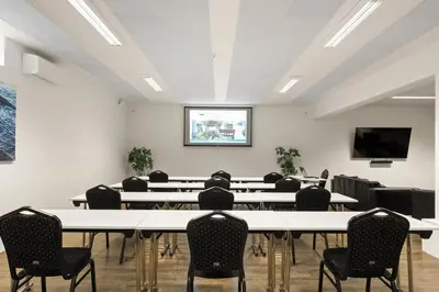 a conference room with tables and chairs and a projection screen at Kinn Hotell Florø in Florø