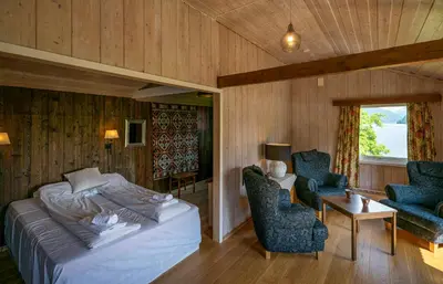 a bedroom with a bed and two chairs and a table at Dragsvik Fjordhotel in Balestrand