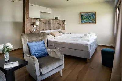 a bedroom with a bed and a chair at Dragsvik Fjordhotel in Balestrand