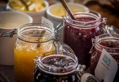 a table with three jars of jam and orange juice at Scandic Parken in Ålesund