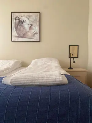 a bed with a blue blanket and a picture on the wall at Askvoll Fjordhotell in Ask