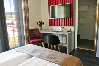 a bedroom with a bed and a desk with a mirror at Tynset Hotel in Tynset