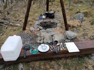 a wooden table with a fire pit in the woods at Hardanger Basecamp in Osa