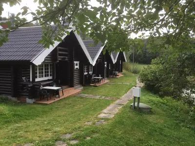 a log cabin with a porch and a yard at Fosheim Hytter in Ron