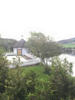 a white house with a porch next to a river at Fosheim Hytter in Ron